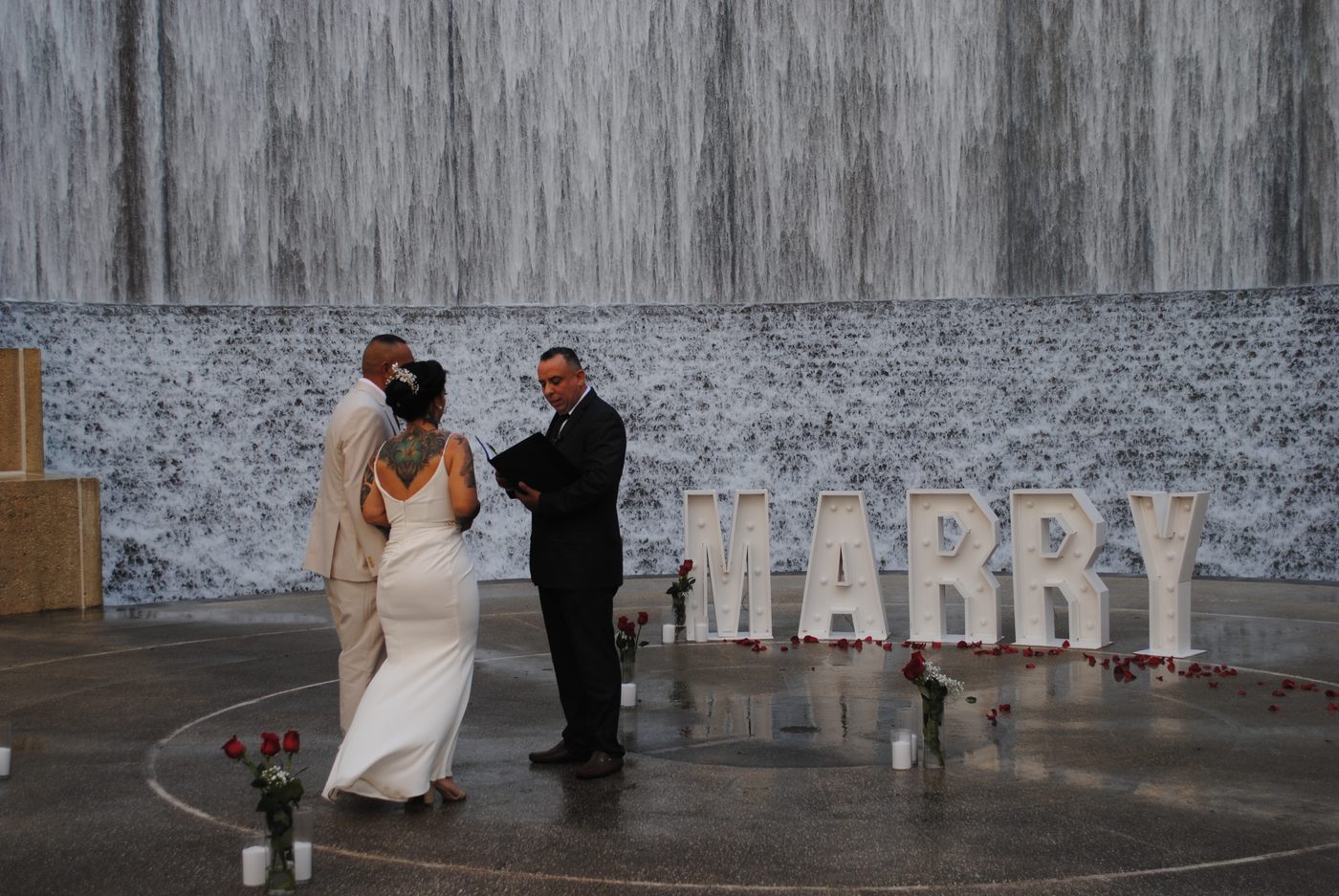 A couple exchanges vows before a stunning waterfall wall backdrop